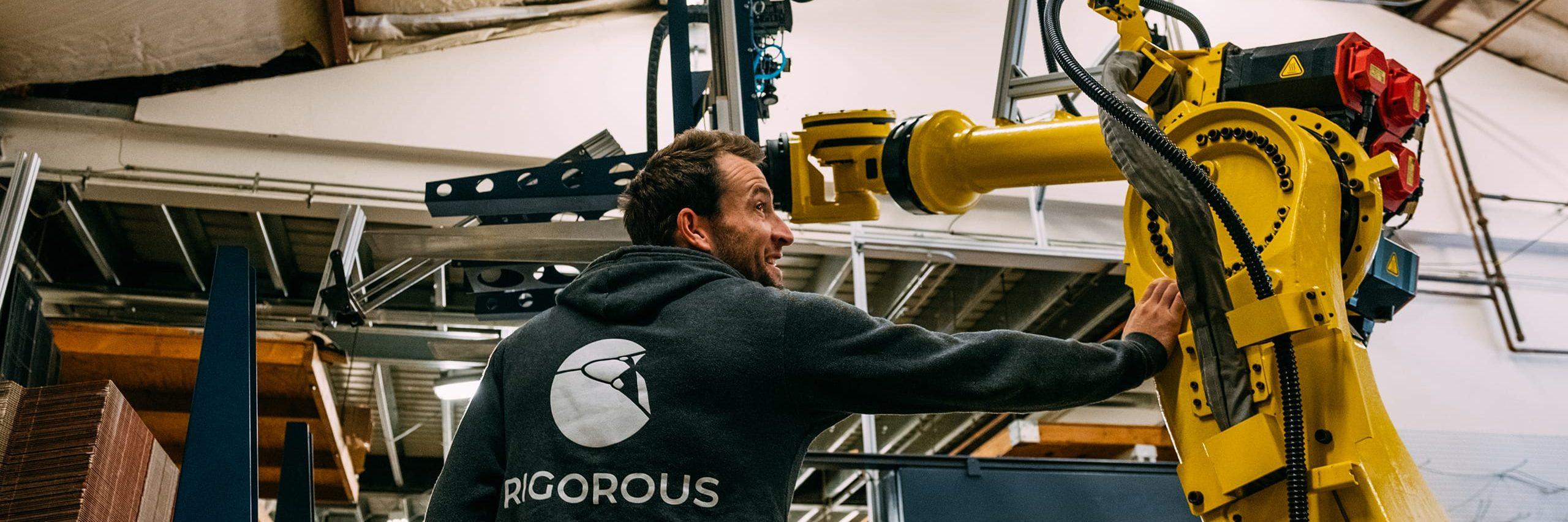 Rigorous employee standing next to Box Hopper robot.